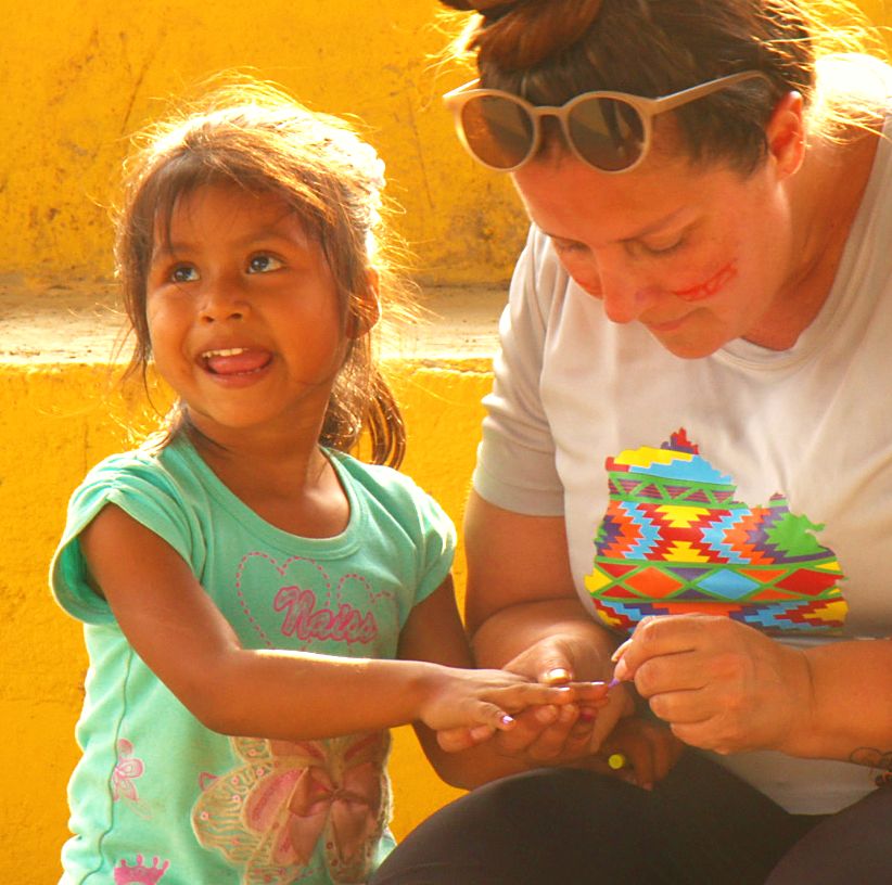 A girl making a bead bracelet with a volunteer