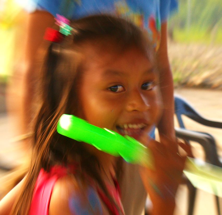 The same girl, grinning, with a toy bubble wand